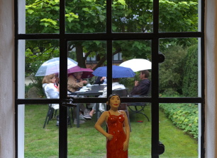 Besucher mit Schirmen am Gartentisch beim offenen Gartentor September 2026